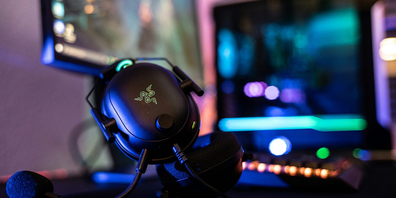 Casque gaming Razer avec microphone devant un setup PC équipé d’un éclairage RGB